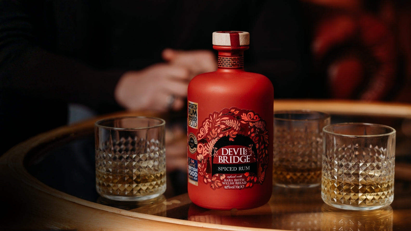 Devil’s Bridge Spiced Rum bottle with glasses on stone surface